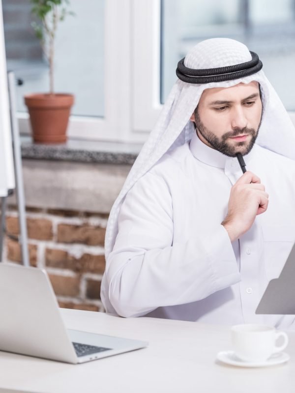 Arabian businessman looking at folder and thinking in office